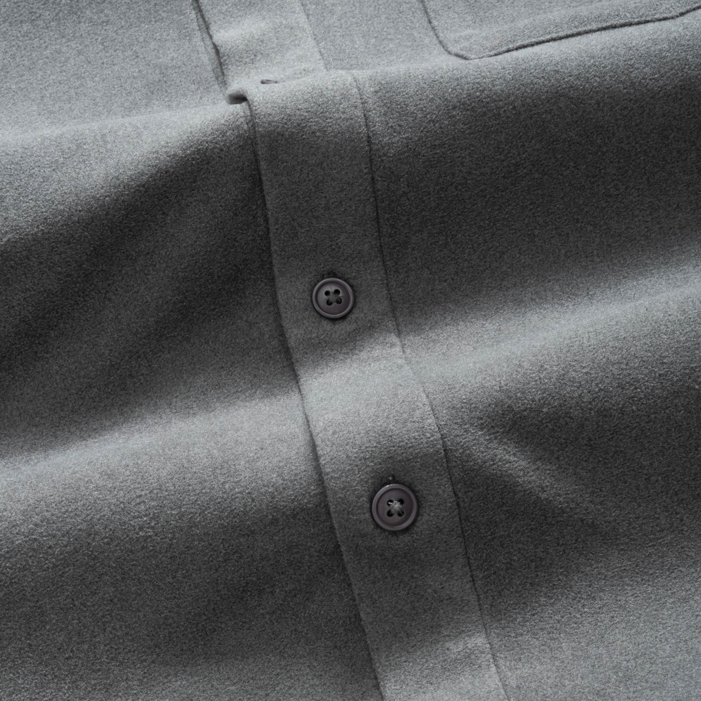 Close-up of a charcoal gray button-up flannel shirt with buttons on a plain background