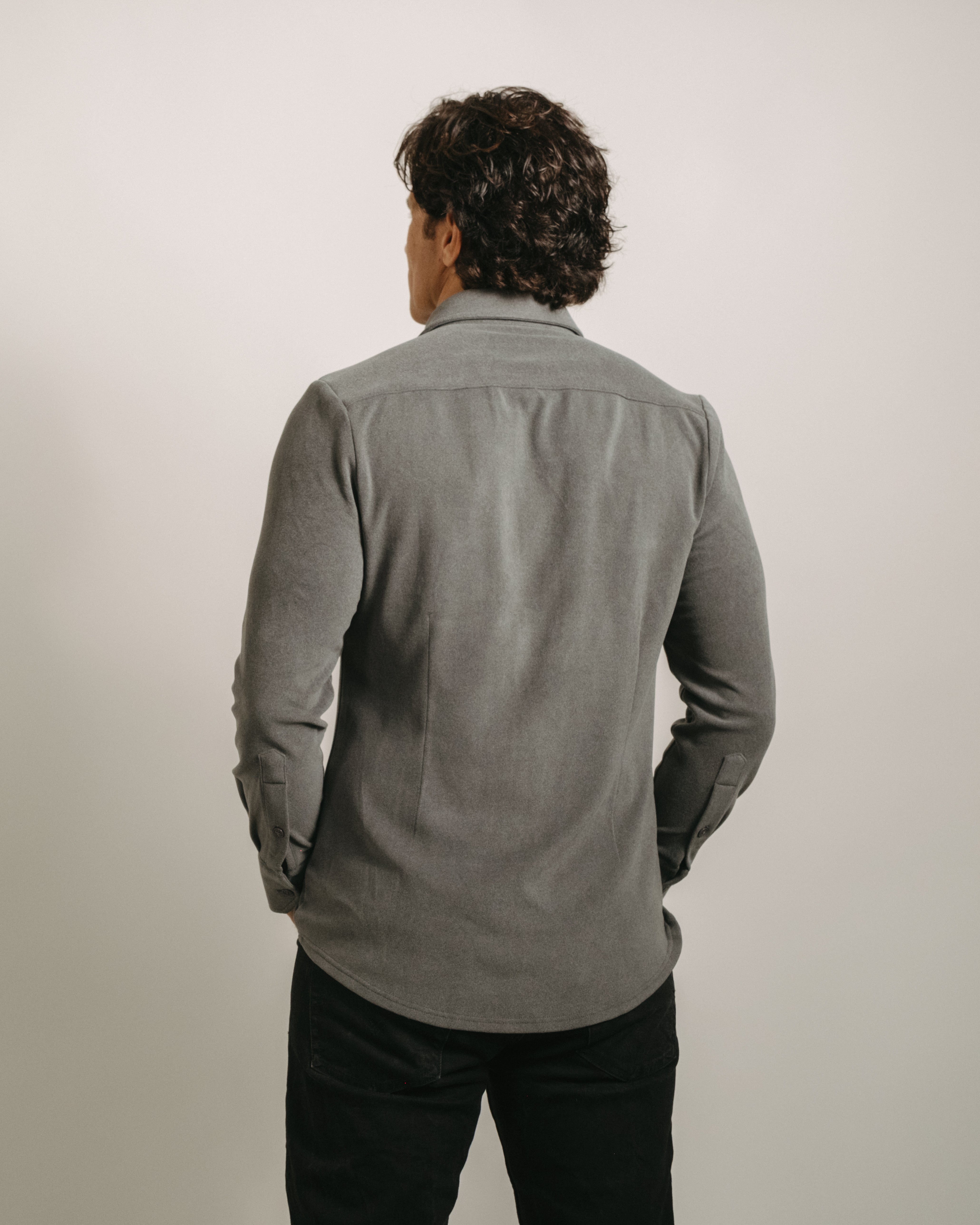 Back angle: Person wearing a charcoal gray button-up flannel shirt with a plain background