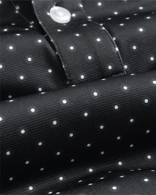 Close-up of a black fabric with white polka dots and a button.