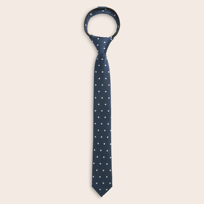 Navy blue zipper tie with white polka dots on a beige background