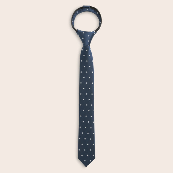 Navy blue zipper tie with white polka dots on a beige background
