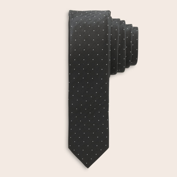 Black tie with white polka dots on a beige background