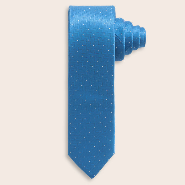 Blue tie with white polka dots on a light beige background