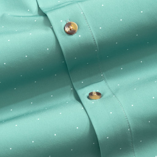 Close-up of a teal fabric with tortoise shell buttons and white polka dots.