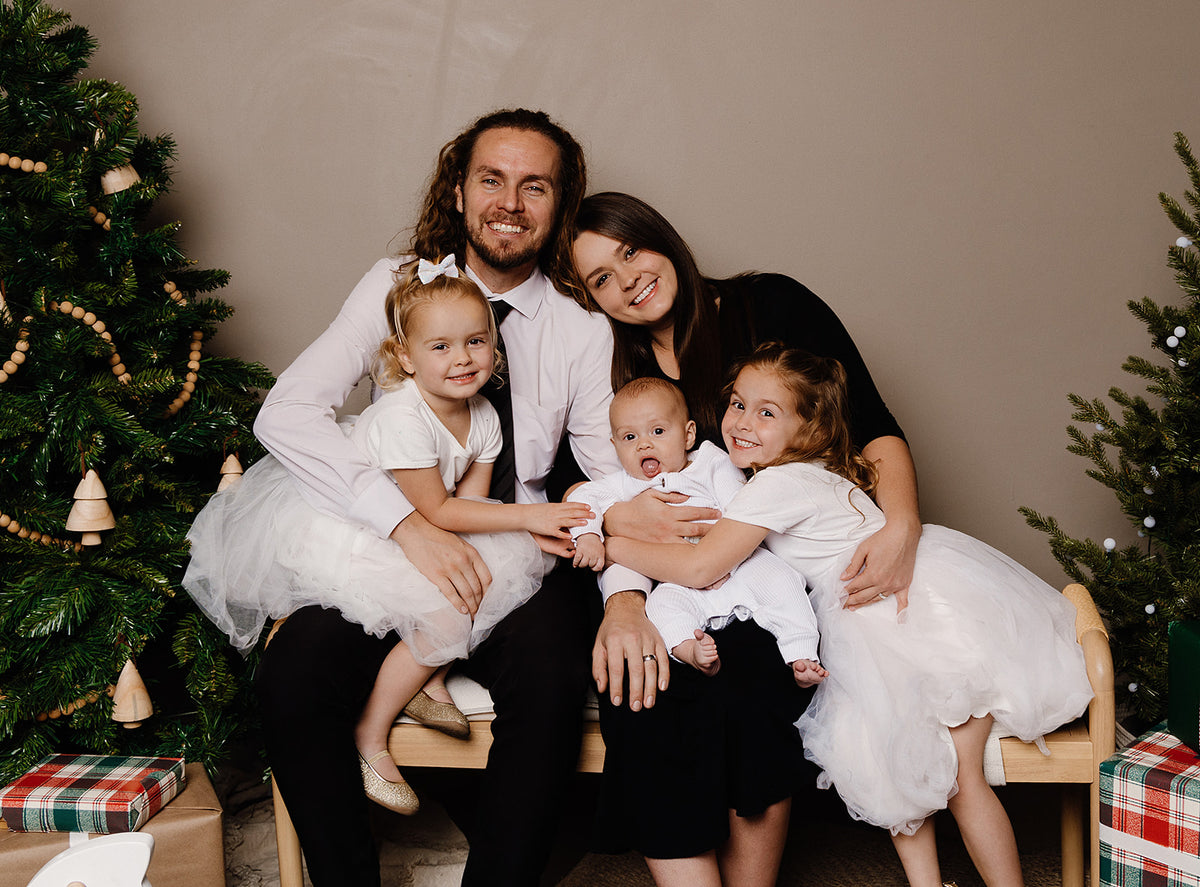 A dad in a white &Collar dress shirt and tie with his wife and kids