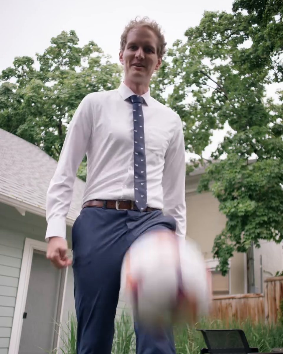 Ben Perkins juggling a soccer ball in a white &Collar dress shirt and tie