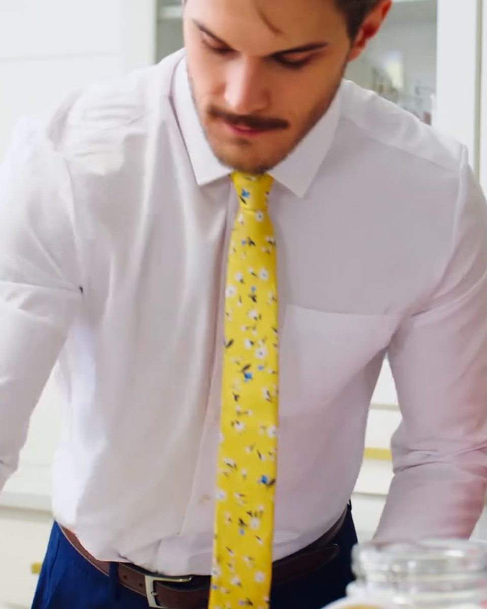A man in a white &Collar dress shirt and yellow tie at the kitchen counter
