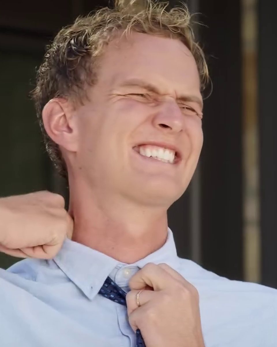 Ben Perkins grimacing as he tightens a stiff dress shirt collar